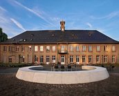 Fassade der BRS Universität für Wirtschaft und Recht, mit modernen Glas- und Steinelementen, umgeben von Grünflächen und einem Gehweg.