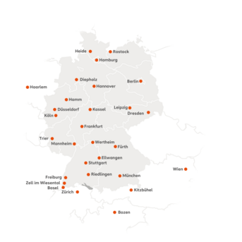 Die Karte zeigt die Standorte der SRH Fernhochschule in Mitteleuropa. Deutschland ist zentriert dargestellt, angrenzende Länder wie die Schweiz, Österreich, Italien beziehungsweise Südtirol und die Niederlande sind ebenfalls sichtbar. Orange Punkte markieren die Studienzentren. In Deutschland sind folgende Städte gekennzeichnet: Berlin, Hamburg, Hannover, Leipzig, Dresden, Düsseldorf, Köln, Hamm, Trier, Mannheim, Frankfurt, Stuttgart, Freiburg, München, Riedlingen, Wertheim, Ellwangen, Fürth, Diepholz, Zell im Wiesental, Heide, Rostock und Kassel. In der Schweiz sind Basel und Zürich markiert, in Österreich Wien und Kitzbühel, in Italien Bozen sowie in den Niederlanden Haarlem.