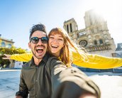 Ein Mann und eine Frau posieren fröhlich für ein Selfie vor einer historischen Kathedrale an einem sonnigen Tag.