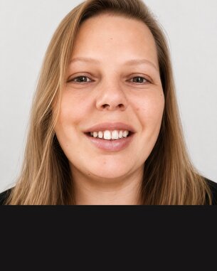 Lächelnde Frau mit langen, blonden Haaren und heller Haut, vor einem neutralen Hintergrund.