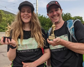 Zu sehen ist Ann-Kathrin Kunzmann zusammen mit einem Begleider. Beide halten eine Trophäe des Neckarsteig in der Hand