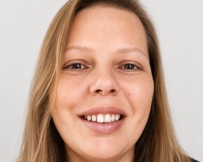 Eine lächelnde Frau mit langen, blonden Haaren und einem neutralen Hintergrund. Sie hat braune Augen und trägt ein schwarzes Oberteil.