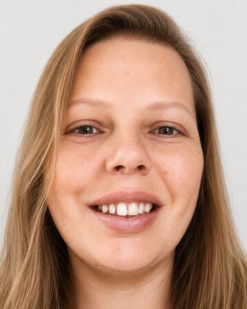 Eine lächelnde Frau mit langen, blonden Haaren und einem neutralen Hintergrund. Sie hat braune Augen und trägt ein schwarzes Oberteil.
